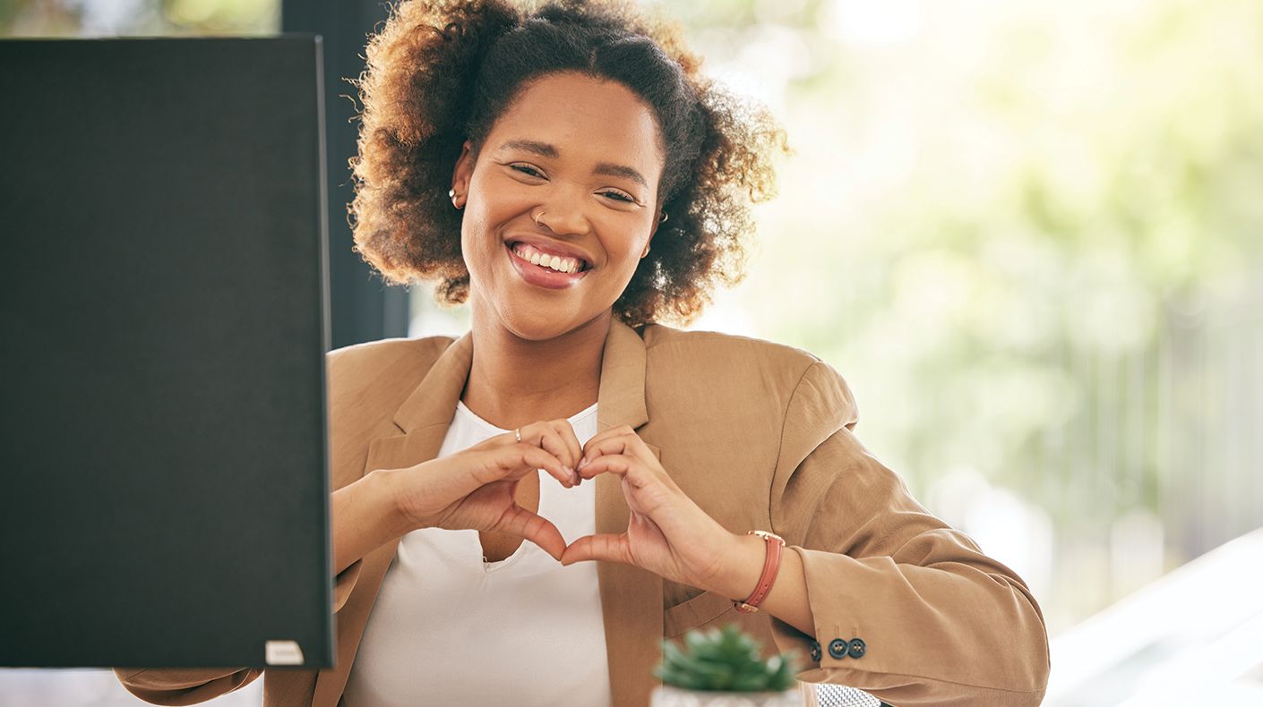 woman at computer making heart hands for mental health