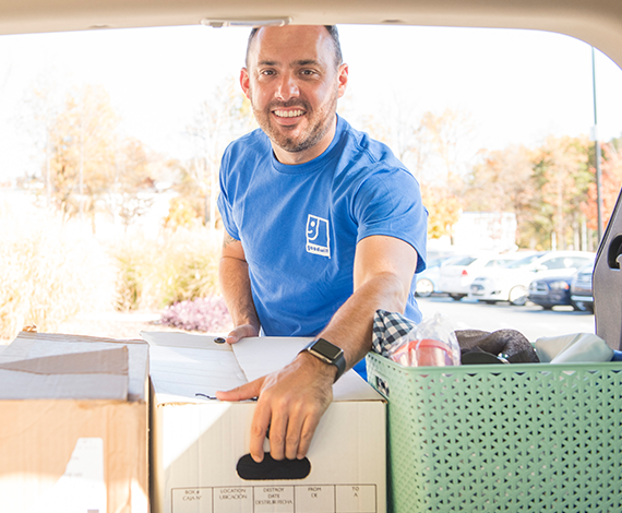 Happy worker grabbing boxes from trunk