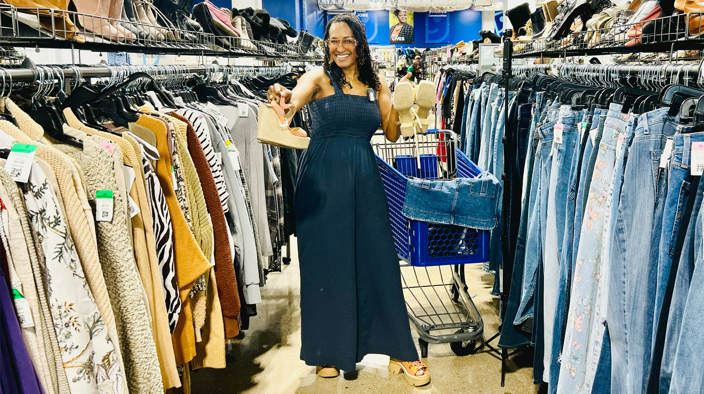 woman standing in between rack of clothes holding sandals
