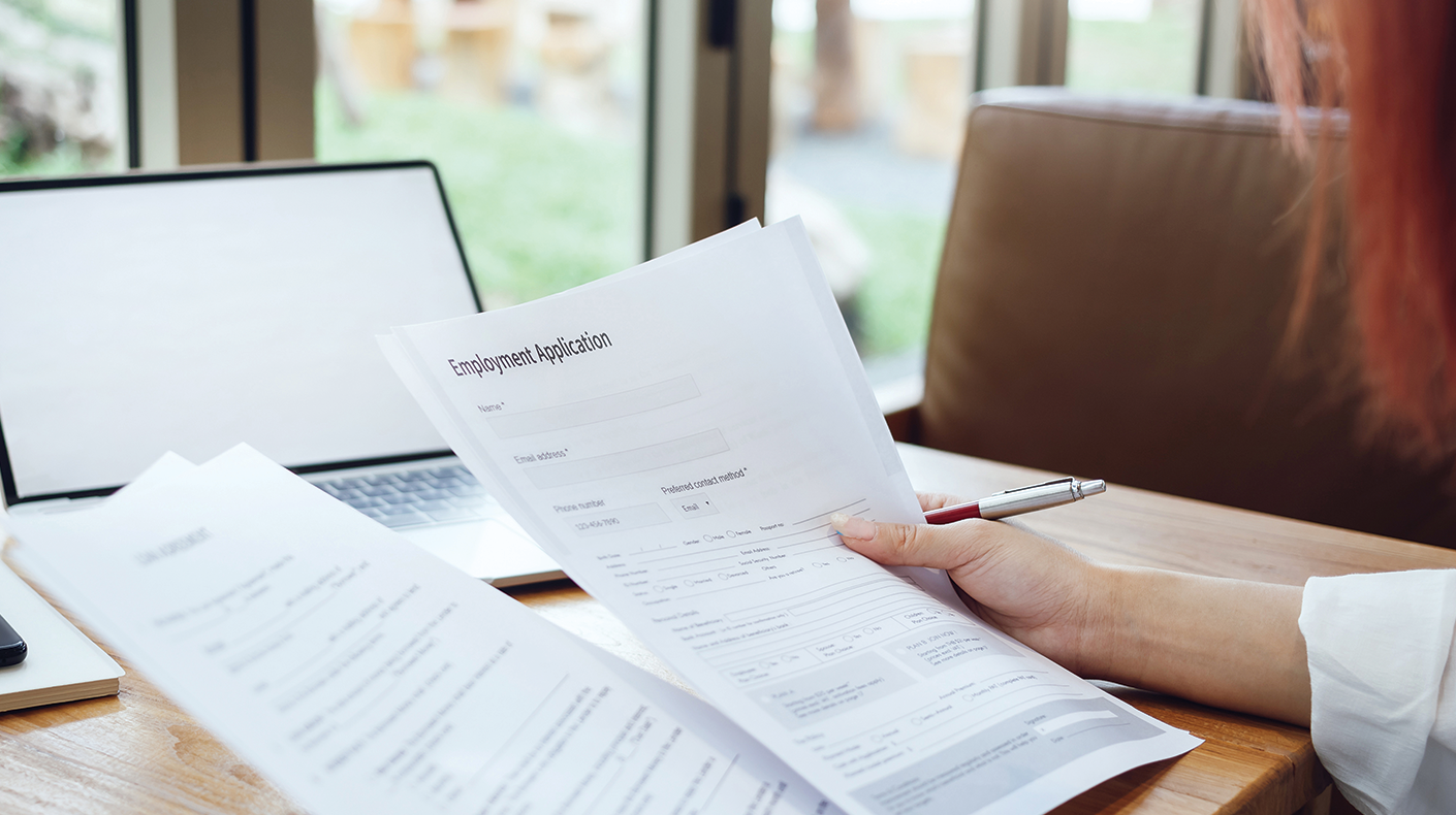 A person's hand holding a pen and papers.