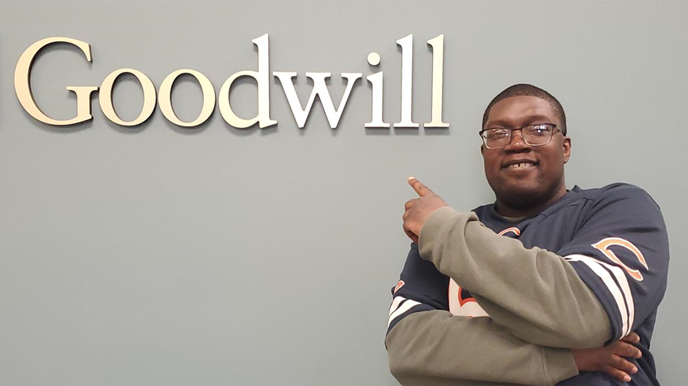 goodwill workforce connection center service recipient pointing at goodwill logo