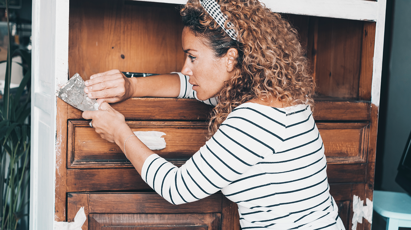 woman refinishing a dresser