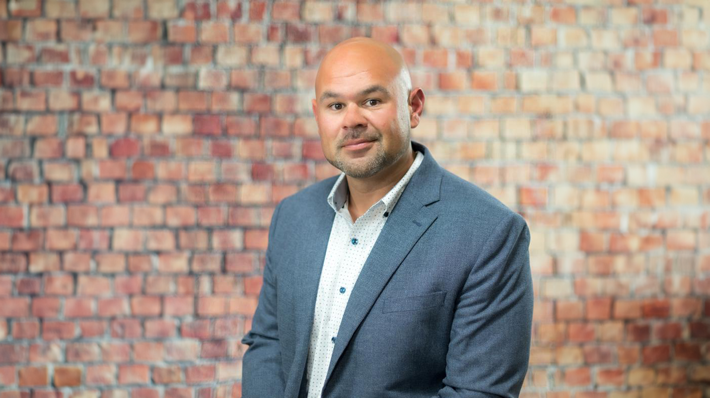 Goodwill employee in a suit jacket in front of a brick wall
