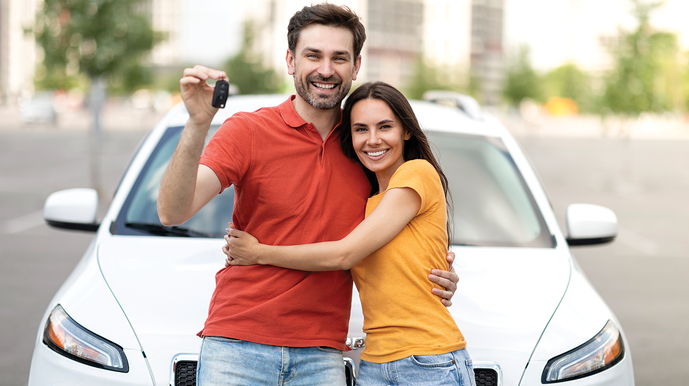 Couple standing in front of a car to be donated to Goodwill