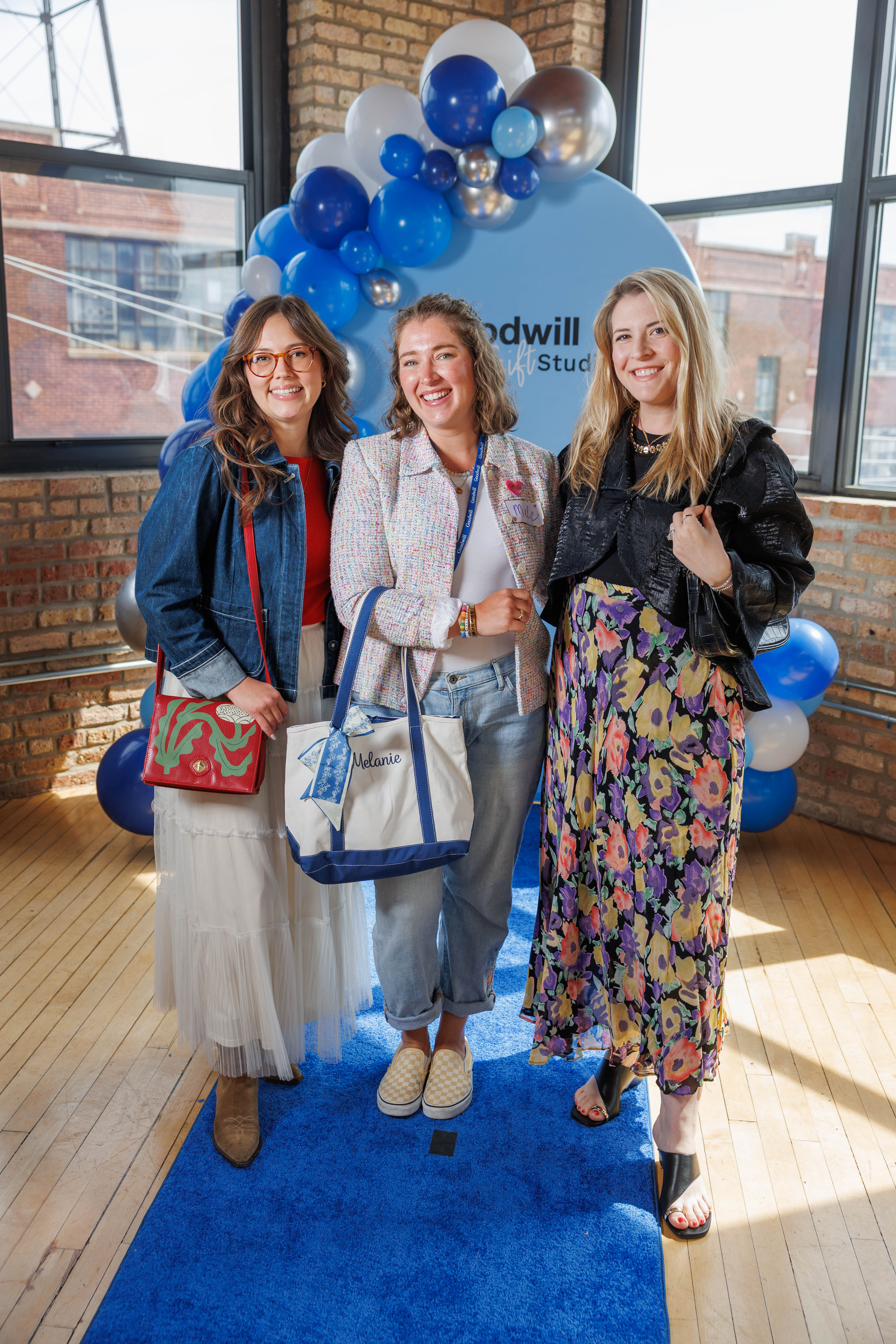 Three people standing on a blue carpet step and repeat