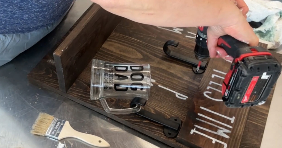 Hands working a power drill on a shelf