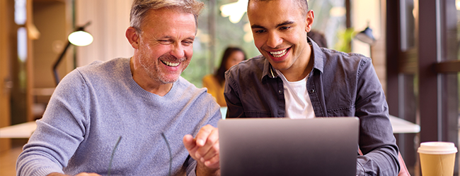 two men in front of a laptop