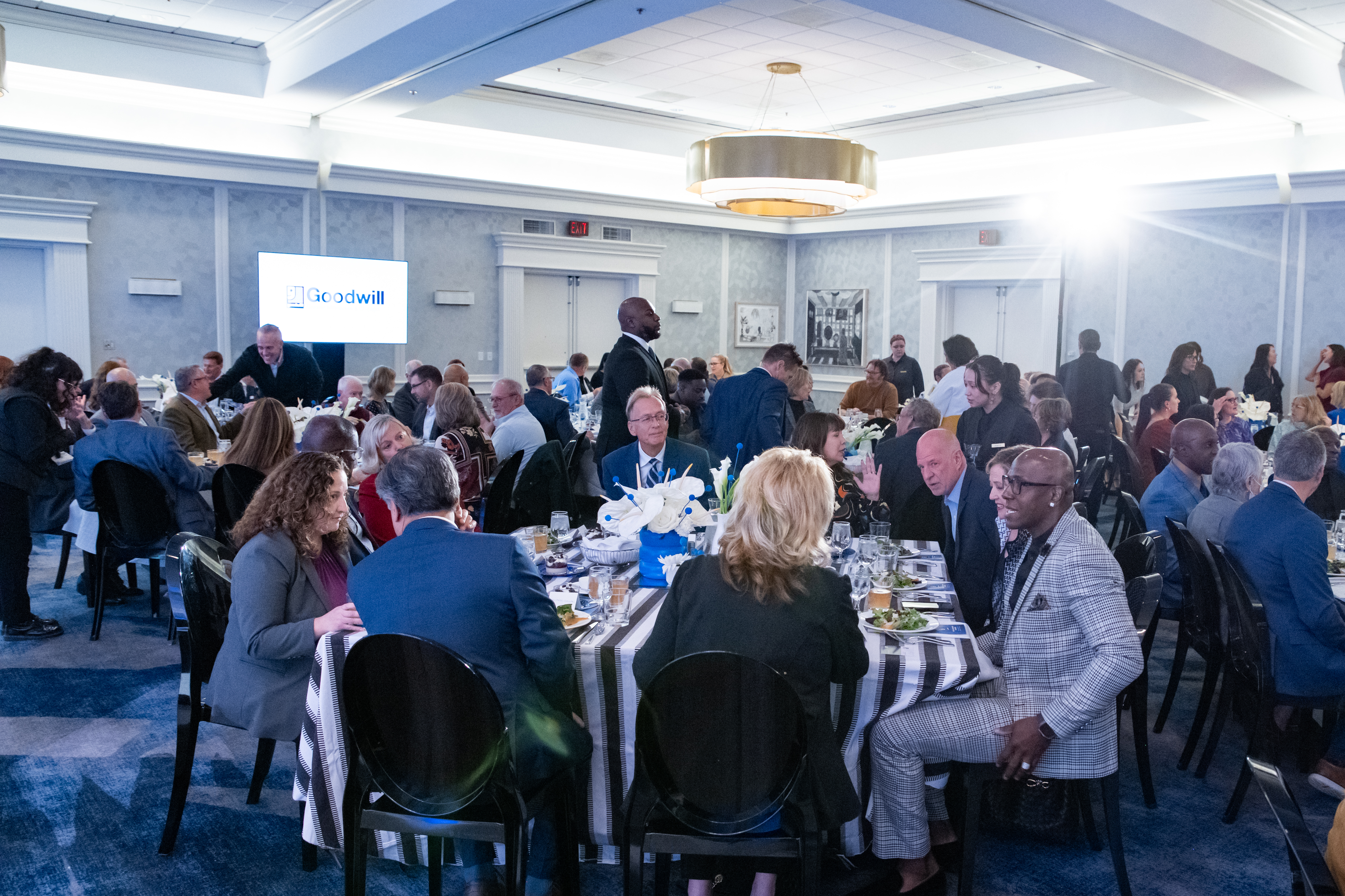people sitting around tables at the goodwill new lives luncheon