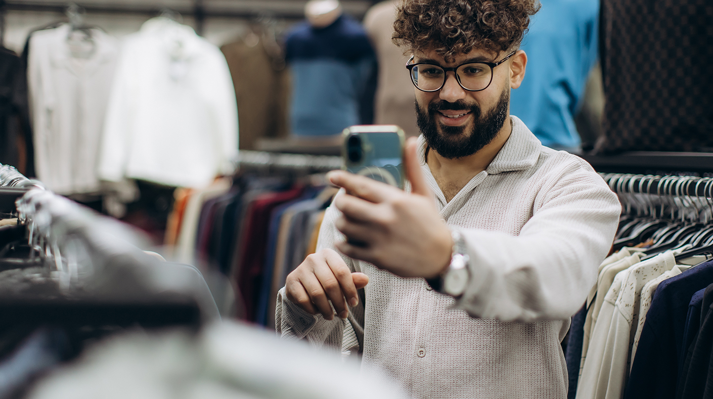 Person holding a phone in between clothing racks