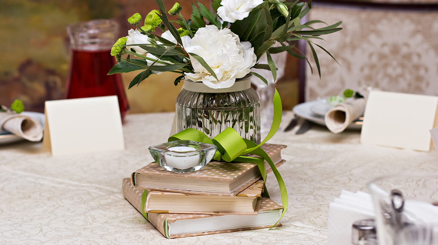 Thrifted Books as Wedding Centerpieces Stacked books with a candle and floral arrangement