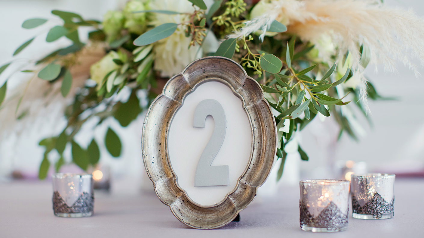 Thrifted Frame Table Number for Wedding A photo frame and votive candles next to a floral arrangement