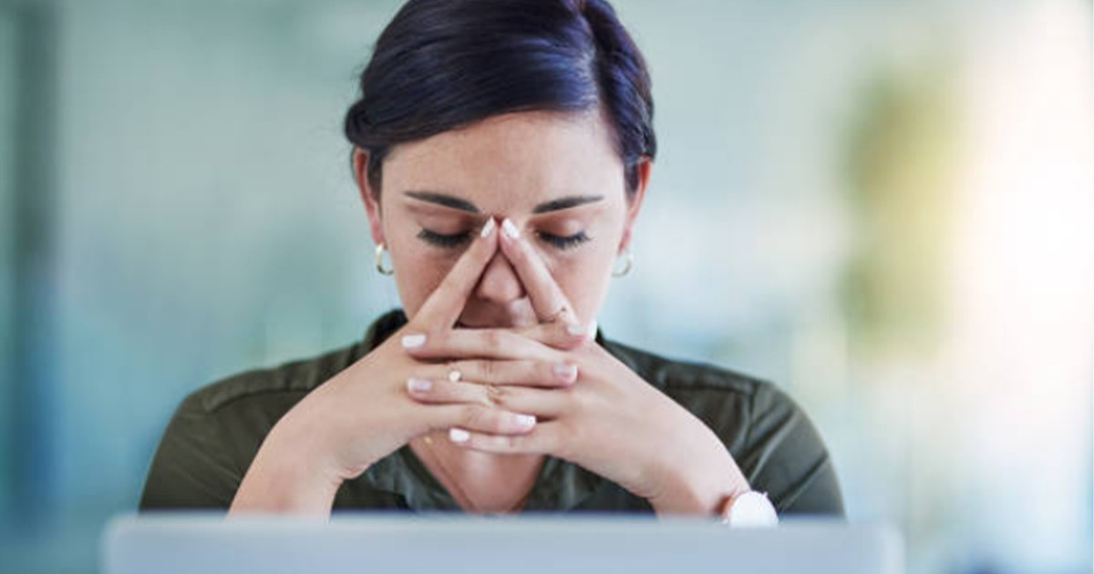 woman with head down, fingers at eyes