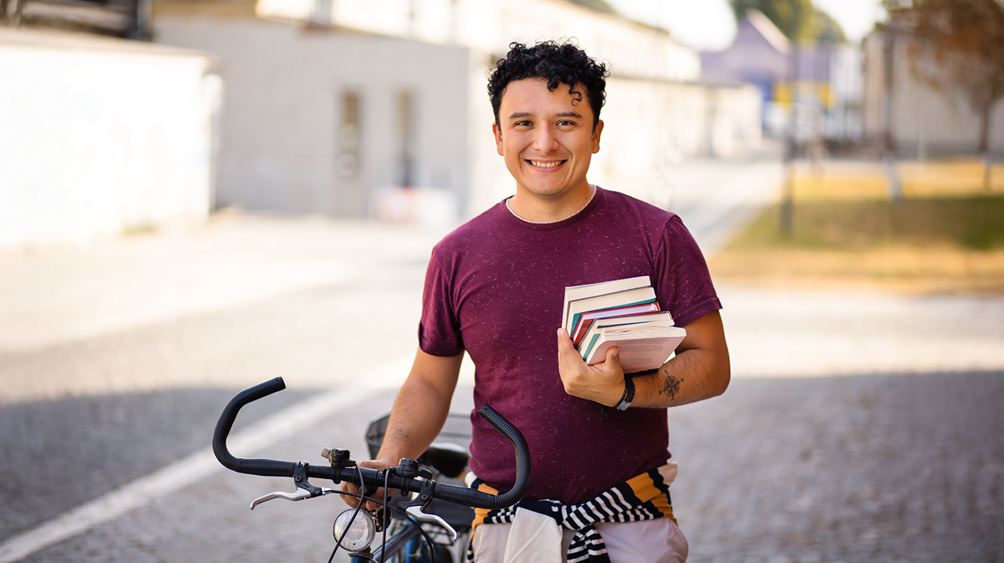man holding books and a bike to donate to Goodwill