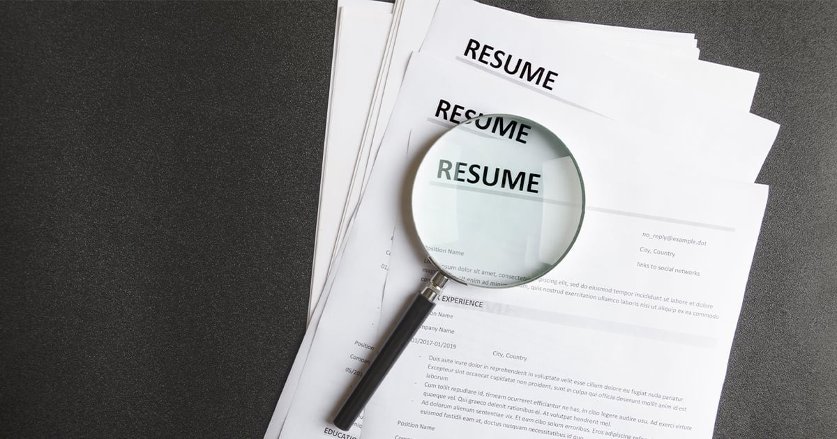 stack of resumes with magnifying glass