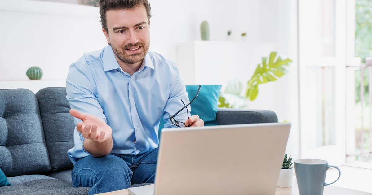 man on couch talking into laptop