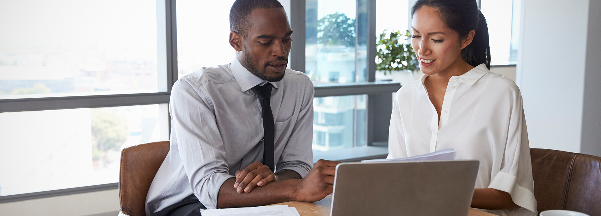 man and woman talking in front of laptop